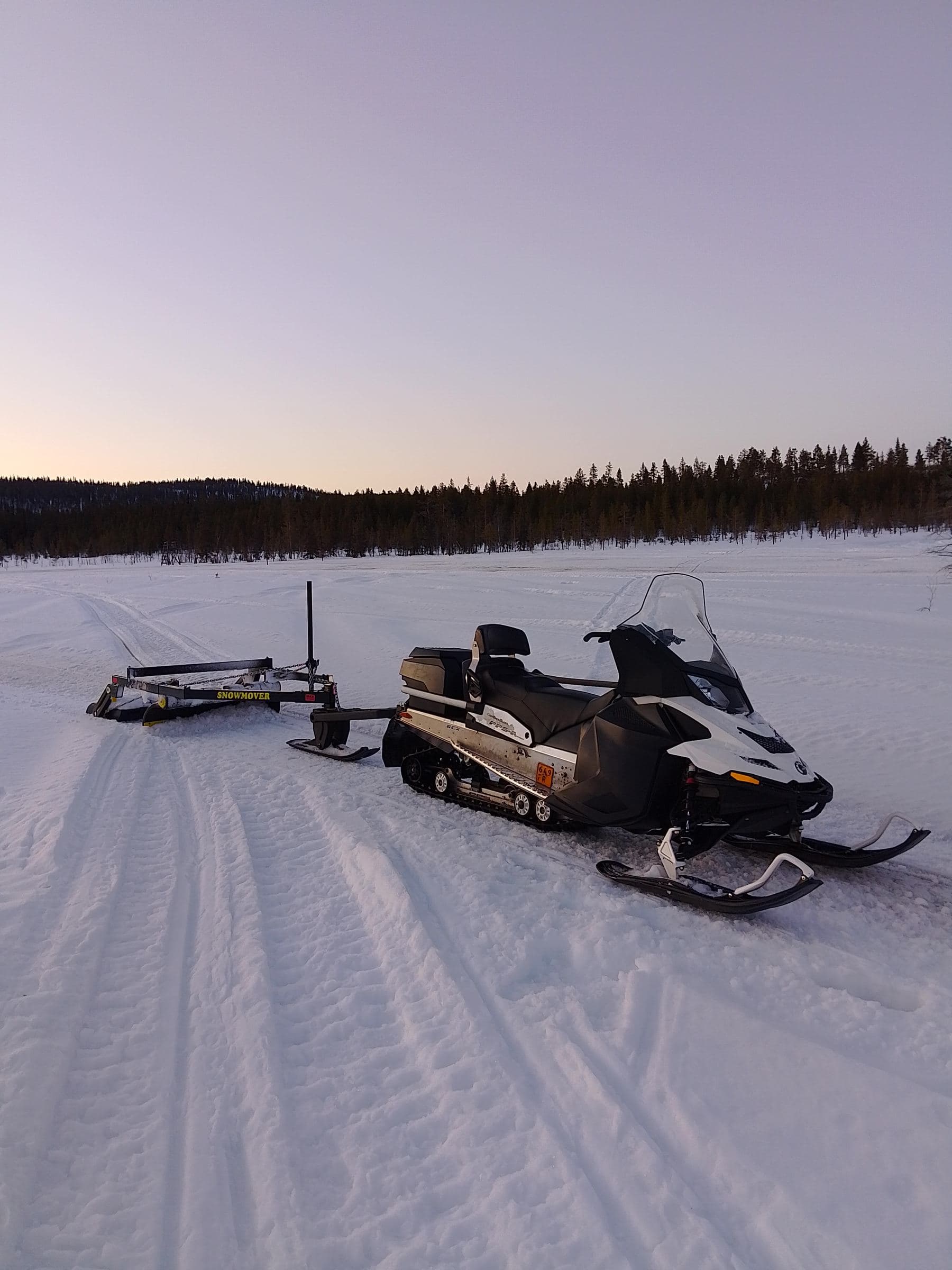Moottorikelkka ja lanausreki reittien kunnossapidossa iltahämärässä